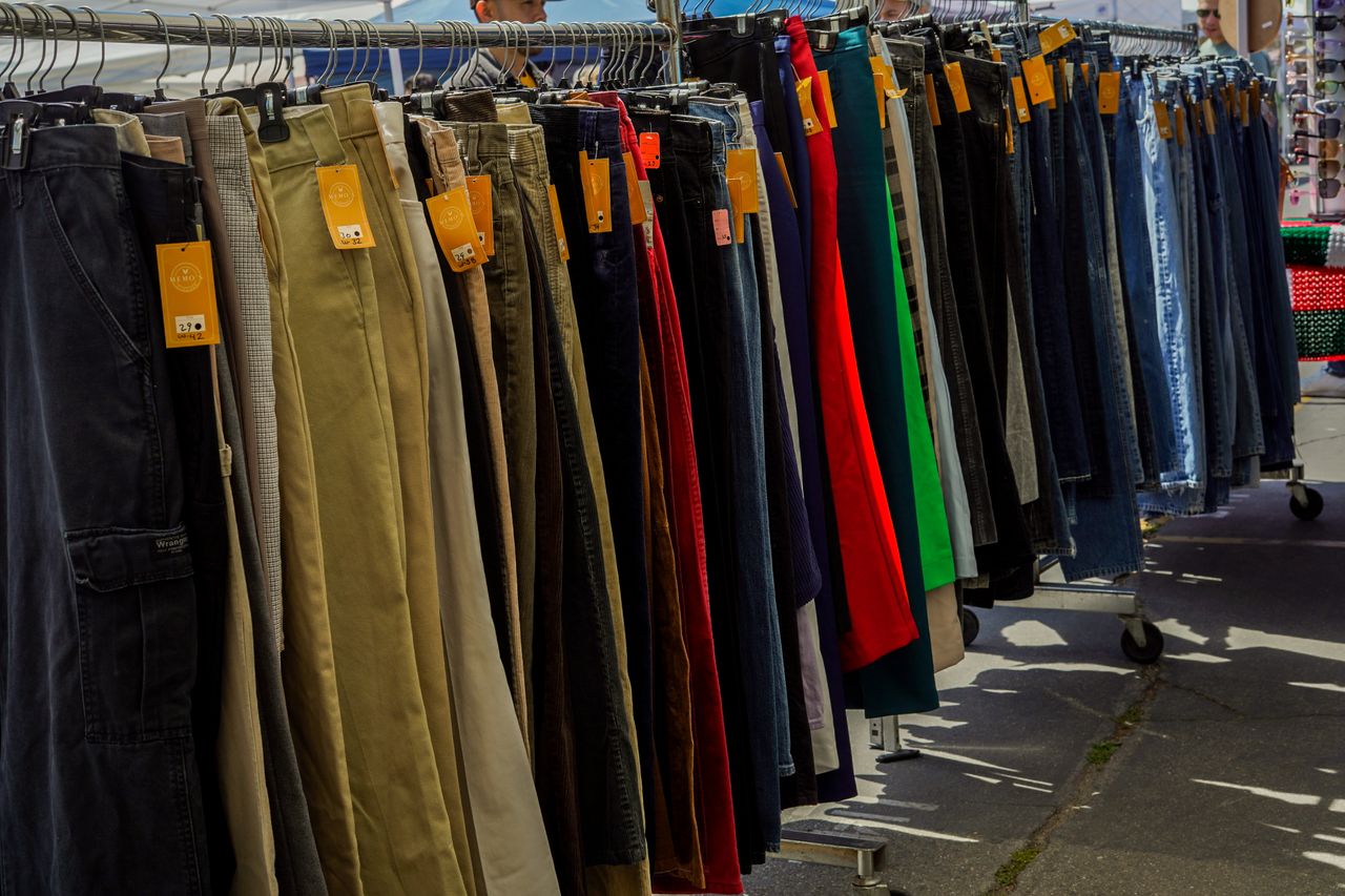 Vibrant collection of trousers showcasing various styles at a busy outdoor market stall.