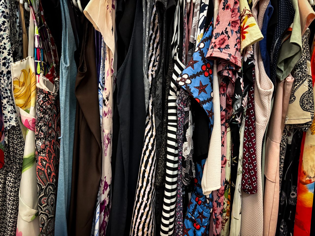 Vibrant collection of assorted vintage clothes hanging on a rack, showcasing patterns and styles.