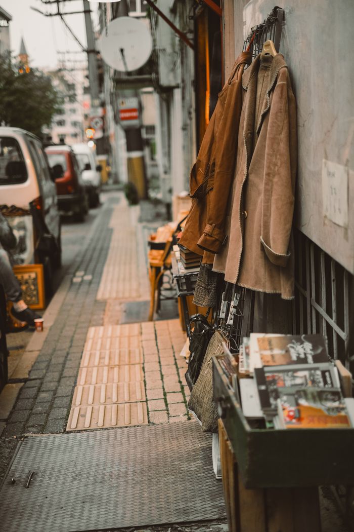 Vintage street market with coats and books on display in an urban alleyway.